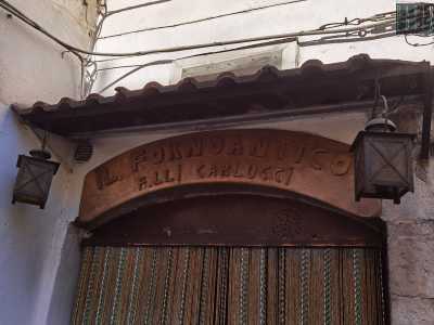 ...coronata da un�insegna curvilinea in legno e due lanternine